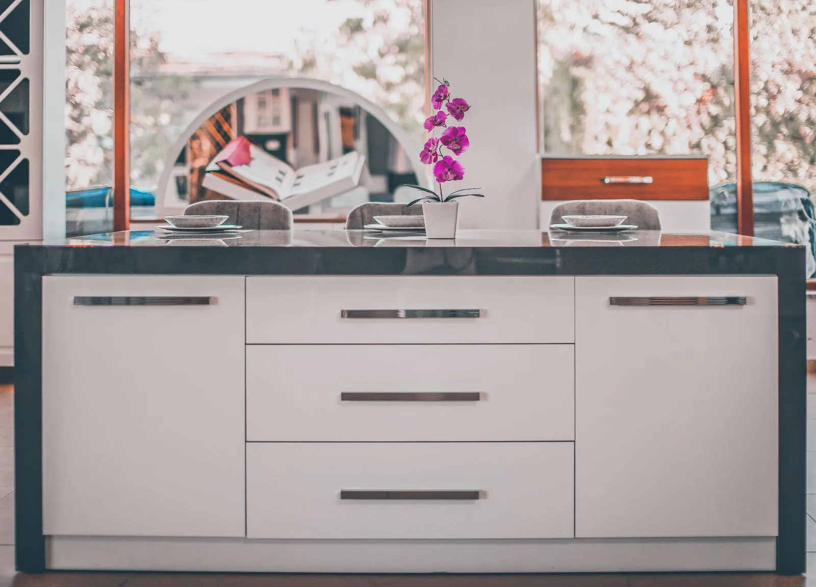 Contemporary kitchen island with an elegant orchid decoration and stylish furniture.